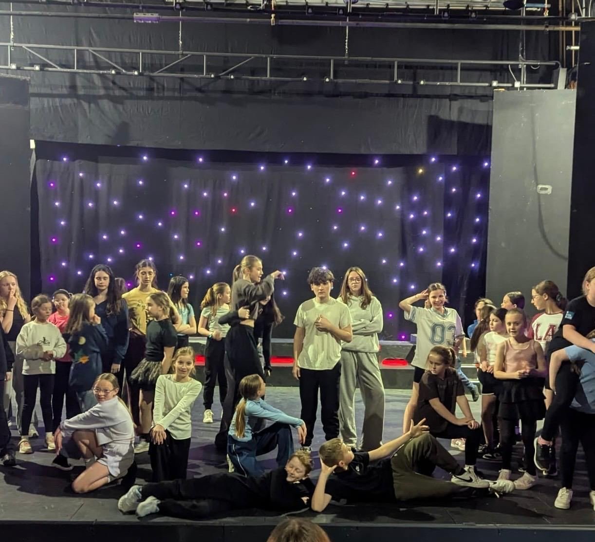 Students performing on stage at the end of a holiday workshop